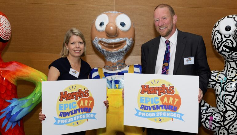 People holding up signs next to morph statue