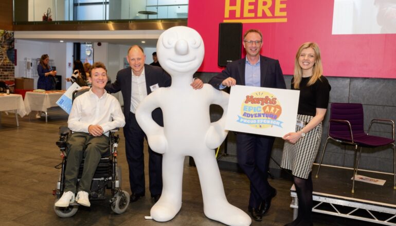 People holding up signs next to morph statue