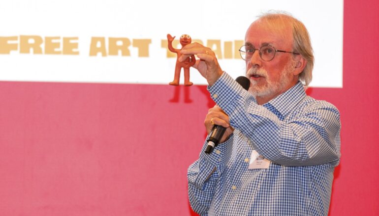 Person making a speech while holding up small morphs statue