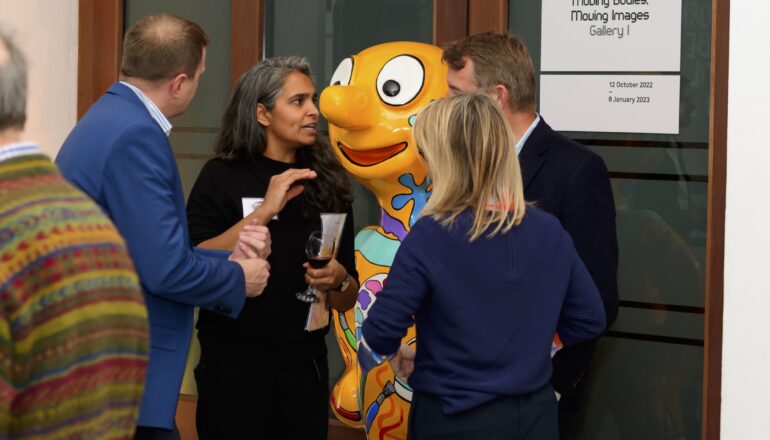 People talking in front of a sculpture