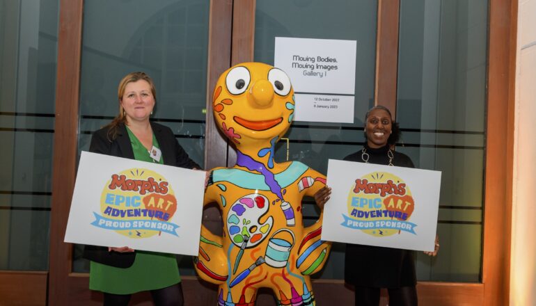 People holding up signs next to a sculpture