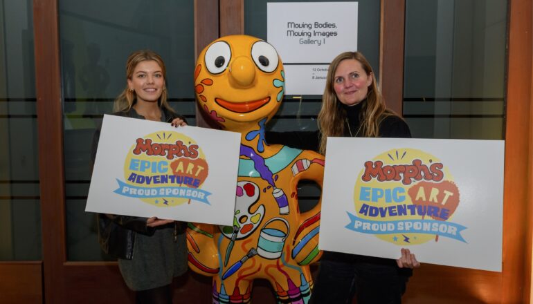 People holding up signs next to a sculpture