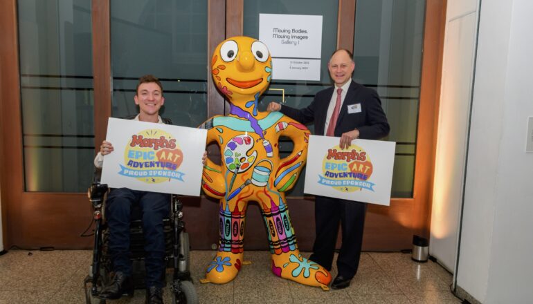 People holding up signs next to a sculpture