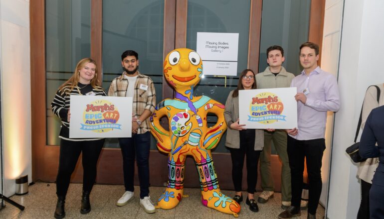 People holding up signs next to a sculpture